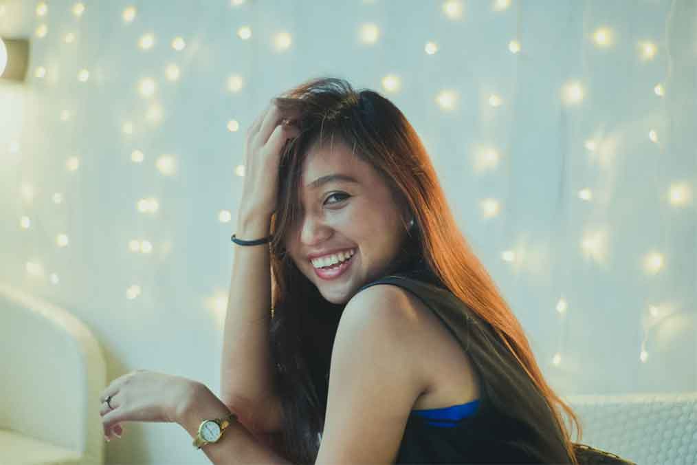 A photo of a smiling Filipina touching her hair.